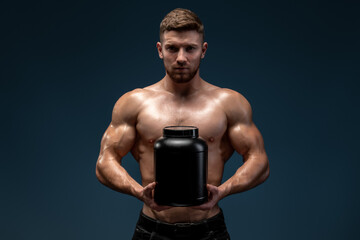 Waist up portrait view of sporty shirtless man stretching to the camera jar with healthy drink, whey protein isolated over black studio background