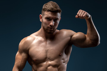 Sporty and healthy muscular man isolated on black background. He showing his muscles and feeling...