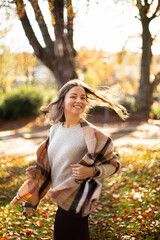 Fototapeta na wymiar Dancing white young european woman with brown hair with warm autumn scarf in the forest