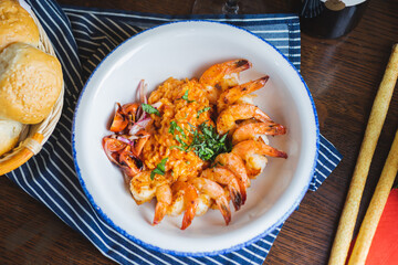 Traditional bright shrimp risotto in a bowl on a table in a restaurant with a beautiful decor in a dark key close-up.
