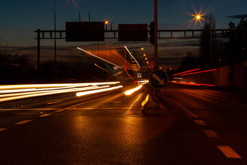The night phantom bus. The light trails of a bus on a main road in the evening. The bus has disappeared, only the lights of its passage remain on the long exposure photograph.
