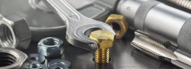 Wrench tightens brass bolt in steel billet. Spanner, bolt, screw and nuts.