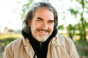 A handsome middle-aged man with long hair and beard outside.
