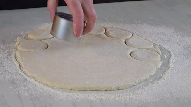 Woman cuts out dough circles for making sweet buns, dounuts.