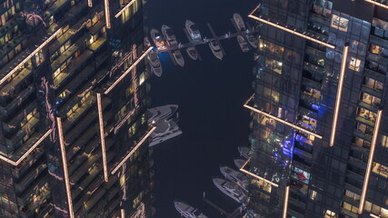 Top view with modern skyscrapers aerial timelapse and water pier of Dubai Marina with night illumination, United Arab Emirates