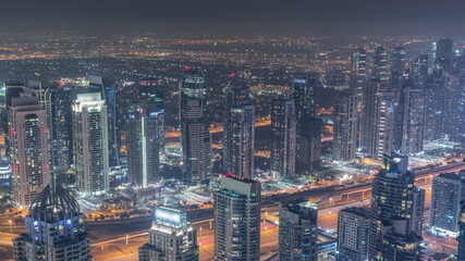 JLT skyscrapers and Dubai marina near Sheikh Zayed Road aerial all night timelapse. Residential buildings