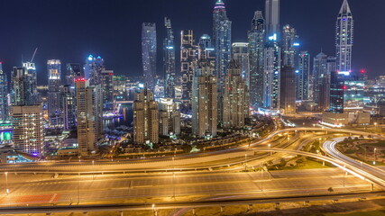 Fototapeta na wymiar Skyscrapers of Dubai Marina near intersection on Sheikh Zayed Road with highest residential buildings all night timelapse