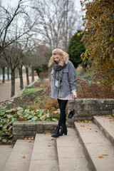 Wunderbare Sch&ouml;ne Frau mit Blondem Haar  und Grauen Mantel in der Winter Zeit in Berlin Gr&uuml;ner Sport Platz