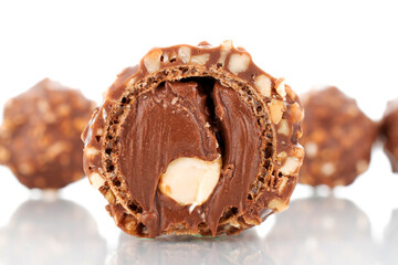 One half of chocolate candy with nuts, close-up, isolated on white.
