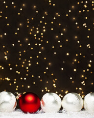 Christmas decorations view of one red and four silver evening balls with white snow on it on dark background with gold colors bokeh. Holidays concept with copy space at the top
