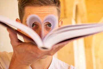 Young handsome white man with brown hair is looking through book pages