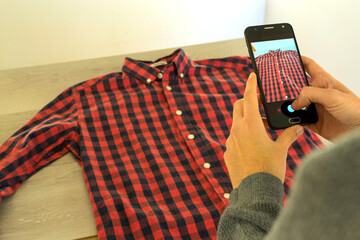 Person photographing a shirt that will be sold in second-hand online stores. Reuse concept.