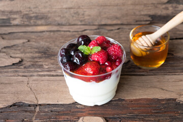 Fruit yogurt has strawberry raspberry blueberry canberry and honey greek white clean In bowl on a wooden background from top view.
