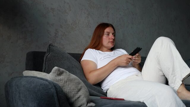 Female hand holding the TV remote control and turn on smart tv at home living room. Technology communication concept