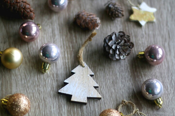 Various wooden Christmas ornaments, golden baubles and pine cones on wooden background. Selective focus.