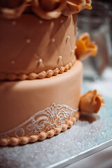 A beautiful brown three-tiered wedding cake with roses. Tasty looking celebration cake. High quality photo