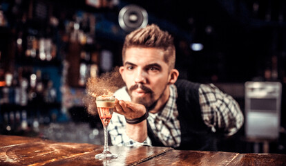 Charismatic bartender pouring fresh alcoholic drink into the glasses at the nightclub