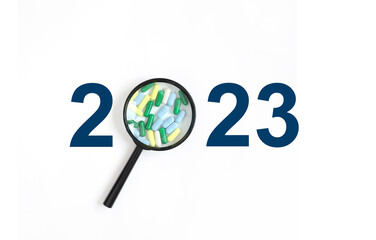 2023 Word Written. medicine concept numbers 2023 instead of number 0 magnifier with pills