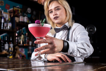 Girl bartender mixes a cocktail on the taproom