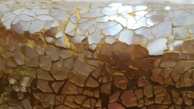 A decorative jar vase made of golden glass fragments reflects light with an elegant shimmer, creating a luxurious, artistic, and warm atmosphere suitable for modern interior visuals.