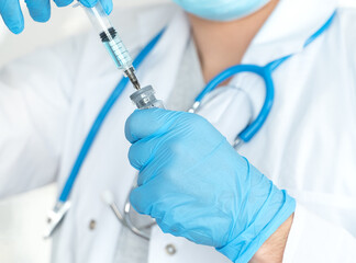 Close up of male doctors hands in gloves fills syringe with drug. Ampoule with vaccine for...