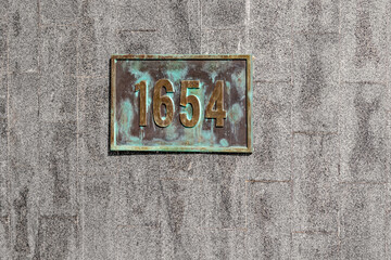 Antique brass plaque with the year 1654 on a granite wall in the Shevchenko City Garden in Kharkiv (Ukraine). Metal plate on stone surface