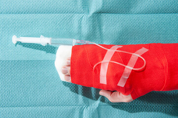 Hand mit Verbandinfusion und Spritze, auf einem grünen, sterilen Tuch