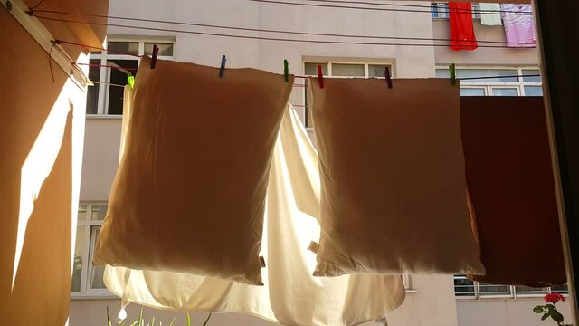 Pillows and a bedspread dry in sunny weather on a balcony, creating a bright domestic scene that reflects freshness, cleanliness, and everyday home life.