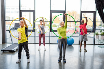 Multiethnic people training with hula hoops in gym.