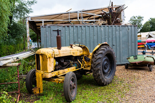 An old retro yellow tractor that has had years of use on the farm but is slowly rusting and falling apart