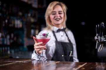 Charming woman barman makes a cocktail in the night club