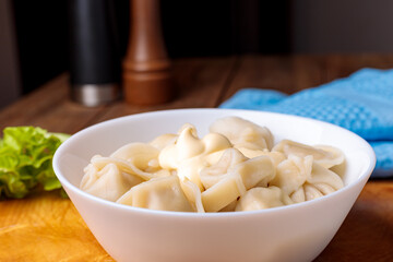 Dumplings in a white plate with salad on a wooden background.