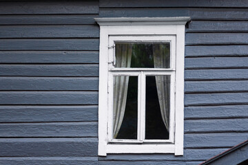 Fototapeta premium Closed window on blue wooden wall. Typical russian old house facade