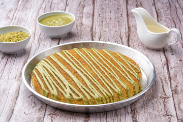 Arabian Traditional Desserts - Cream and cheeses with pistachio flavor and nuts topping on gray background