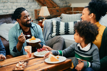 Fototapeta na wymiar Happy black family enjoys while eating cake and talking at home.