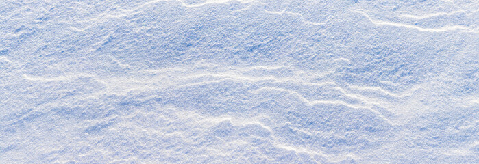 Snowy background, snow-covered surface of the earth after a blizzard in the morning in the sunlight with distinct layers of snow