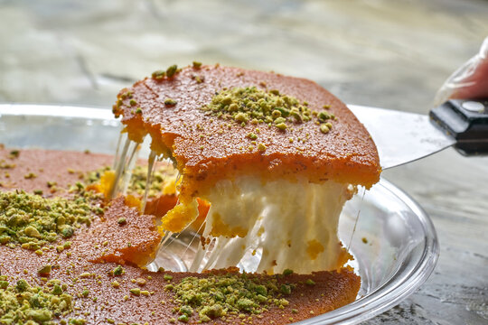 Arabian Traditional Desserts kunafa - Cream and cheeses with pistachio flavor and nuts topping on gray background