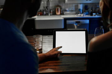 Silhouette over couple's shoulders looking at tablet computer screen at night