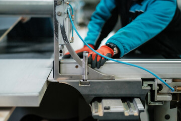 Cnc circular saw sawing chipboard. Process of making cabinet furniture close-up. Worker with gloves at the machine.