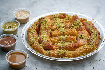 Arabian Traditional Desserts rolls - Cream and cheeses with pistachio flavor and nuts topping on gray background