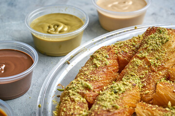 Arabian Traditional Desserts - Cream and cheeses with pistachio flavor and nuts topping on gray background