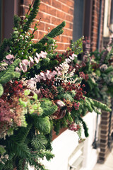 Angled window box arrangement filled with winter seasonal flowers and plants full window