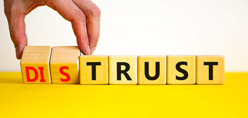 Distrust or trust symbol. Businessman turns wooden cubes, changes words 'distrust' to 'trust'....
