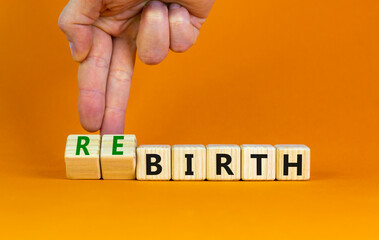 Birth or rebirth symbol. Businessman turns wooden cubes and changes the word birth to rebirth. Beautiful orange table orange background, copy space. Business, birth or rebirth concept.
