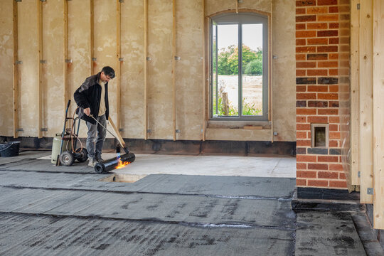 Installation of waterproofing on the concrete foundation by heating and melting rolls of bitumen roofing felt with a propane blowtorch
