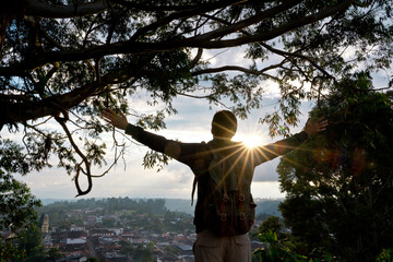 Horizontal view of unrecognizable man sightseeing in Salento viewpoint at sunset. Horizontal view of traveler man from behind with arms wide open. People and travel destination in Colombia