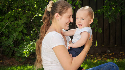 Happy smiling 9 months old baby boy with smiling mother having fun together at garden
