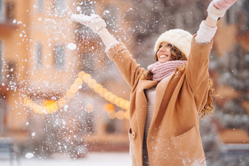 Happy woman in winter style clothes against the backdrop of garland lights. Winter fashion, holidays concept.