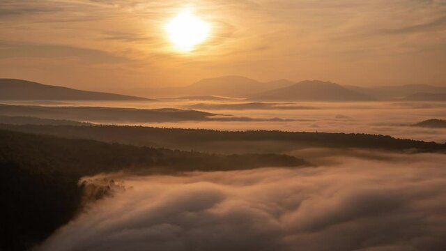 Stunning orange sunrise with sea clouds drifing in a valley among mountains. Famous Aigir rocks at South Urals, Russia