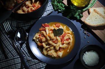 Cibo italiano. Piatto tipico della trippa di manzo con salsa di pomodoro con crostini di pane nel piatto sul tavolo. Direttamente sopra.